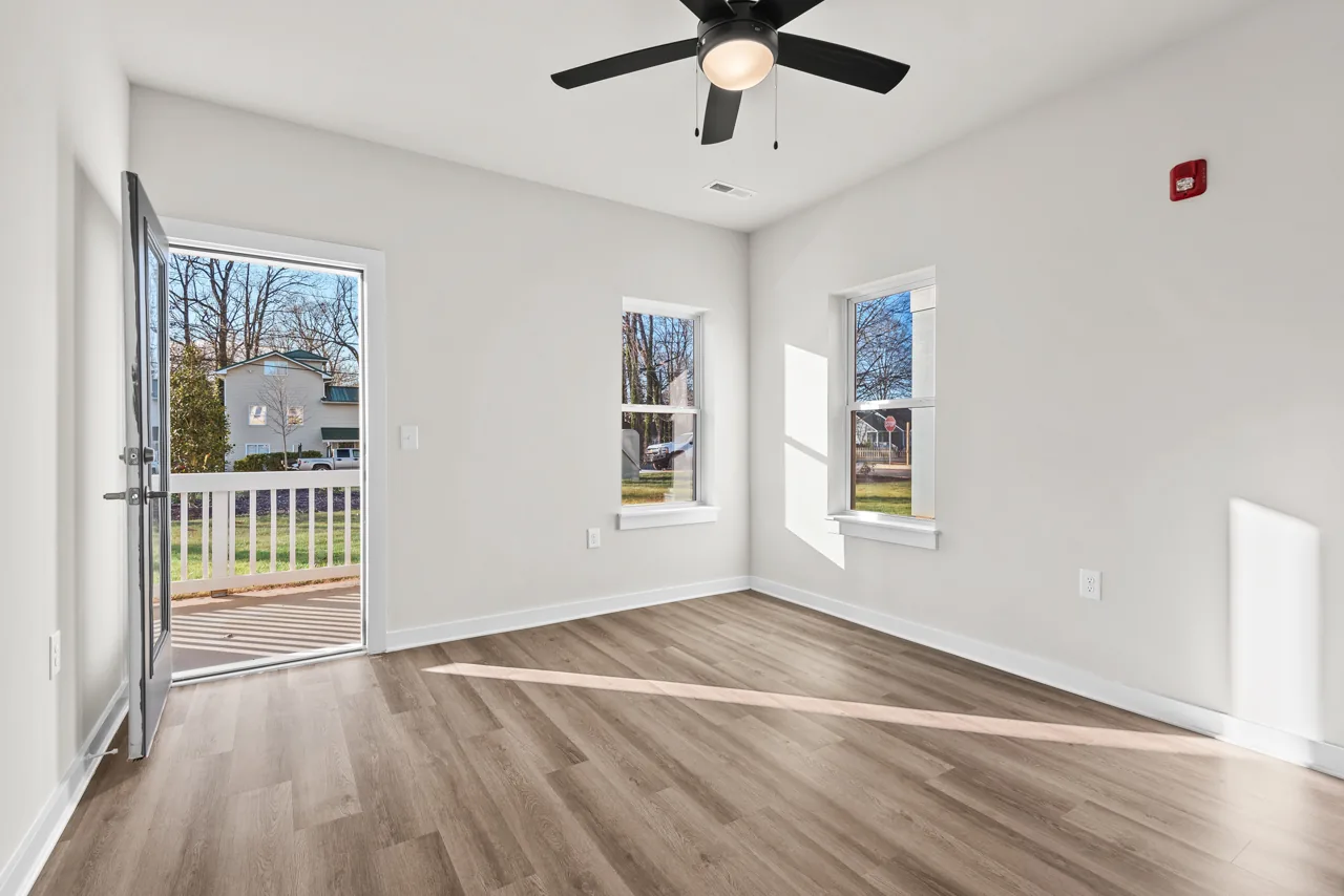 Bedroom at Eleventh Street Apartments with a ceiling fan, wood-look flooring, and a door to the porch