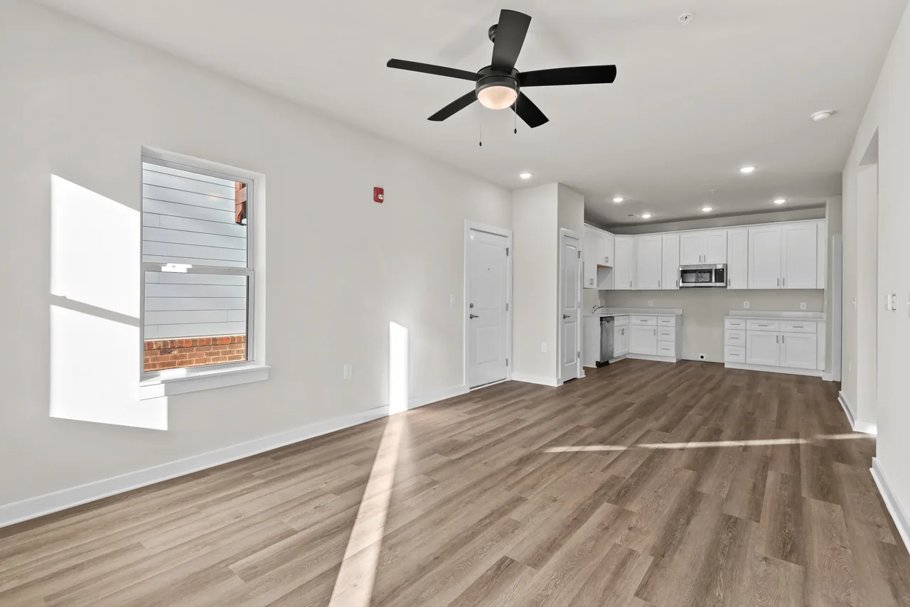 Open living room with wood-look flooring and a white kitchen